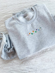 Ash adult basic fleece with lucky charm marshmallows embroidered on chest, seen on flat lay - Little Mama Shirt Shop
