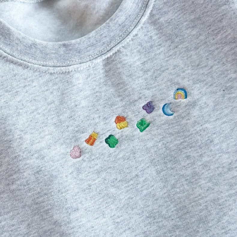 Ash adult basic fleece with lucky charm marshmallows embroidered on chest, seen on flat lay - Little Mama Shirt Shop
