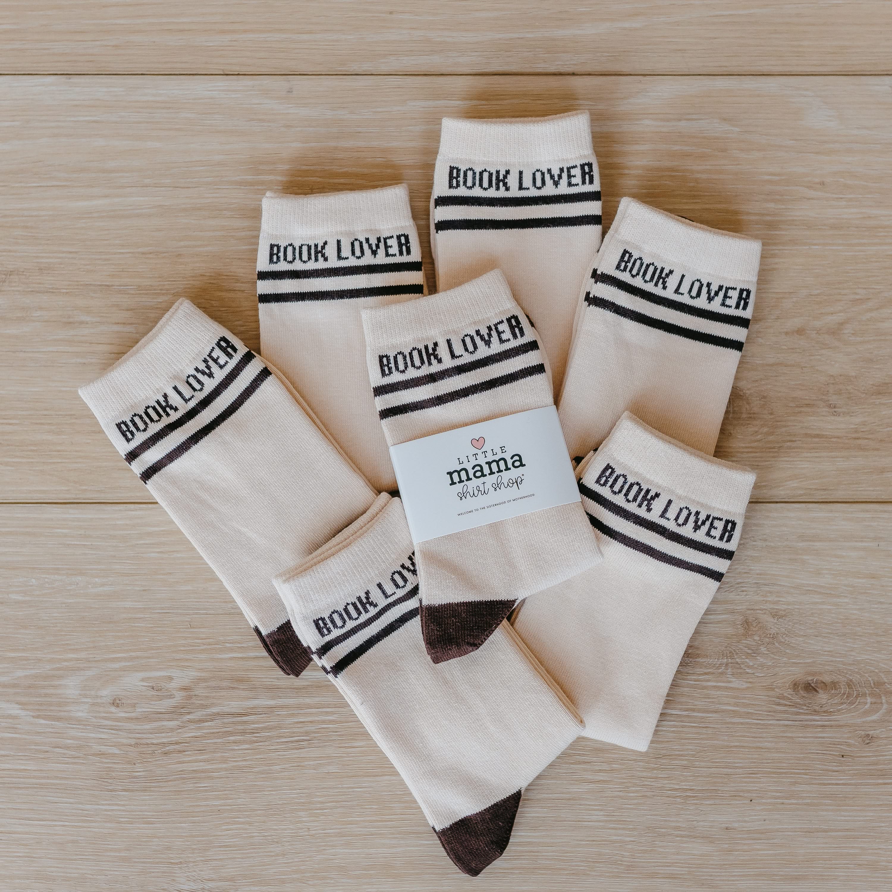 Pair of tan athletic-style socks with black stripes and subtle “Book Lover” text near the cuff. Flat lay picture - Little Mama Shirt Shop