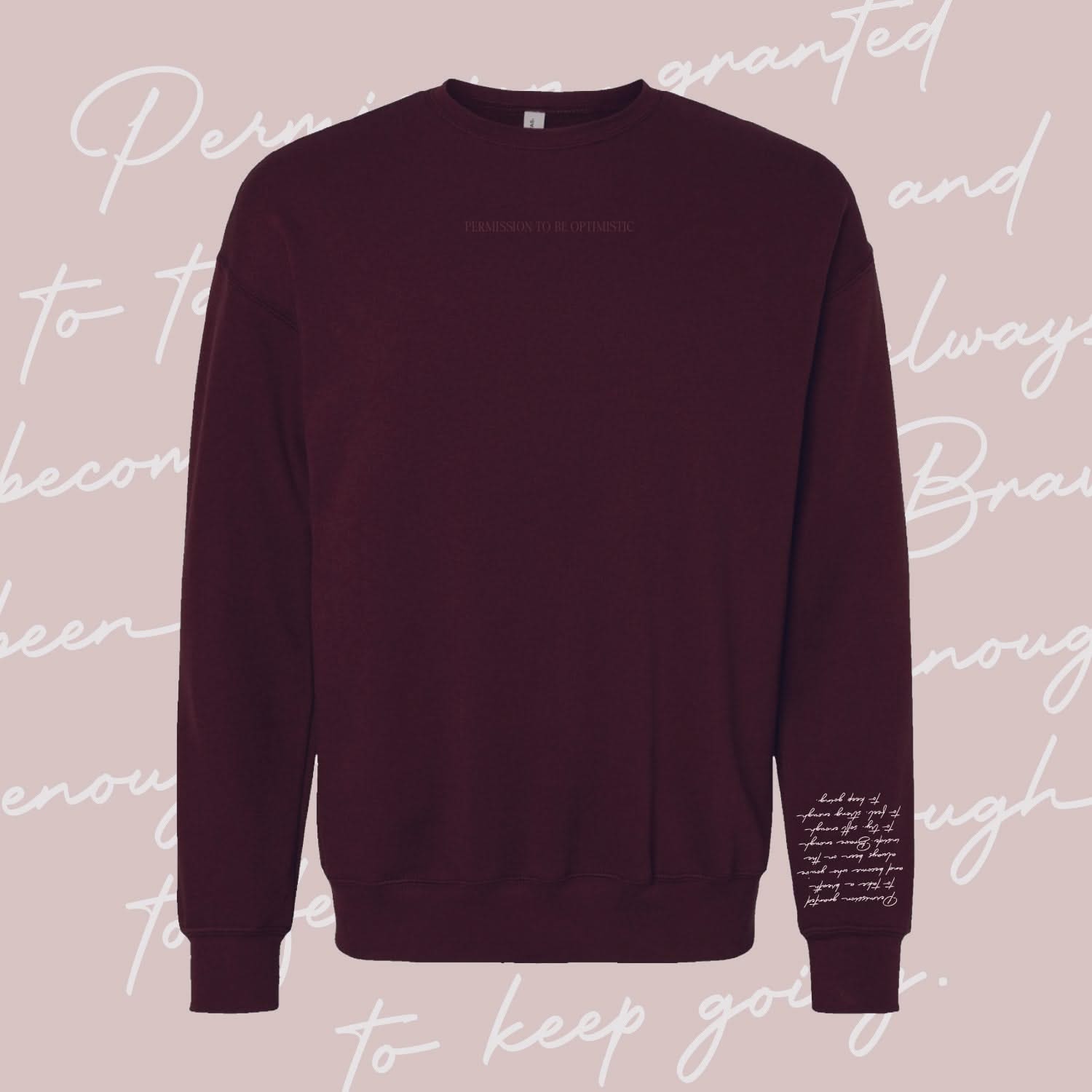 Maroon crewneck with "Permission To Be Optimistic" on chest and permission to be paragraph printed on sleeve, shown on flat lay - Little Mama Shirt Shop