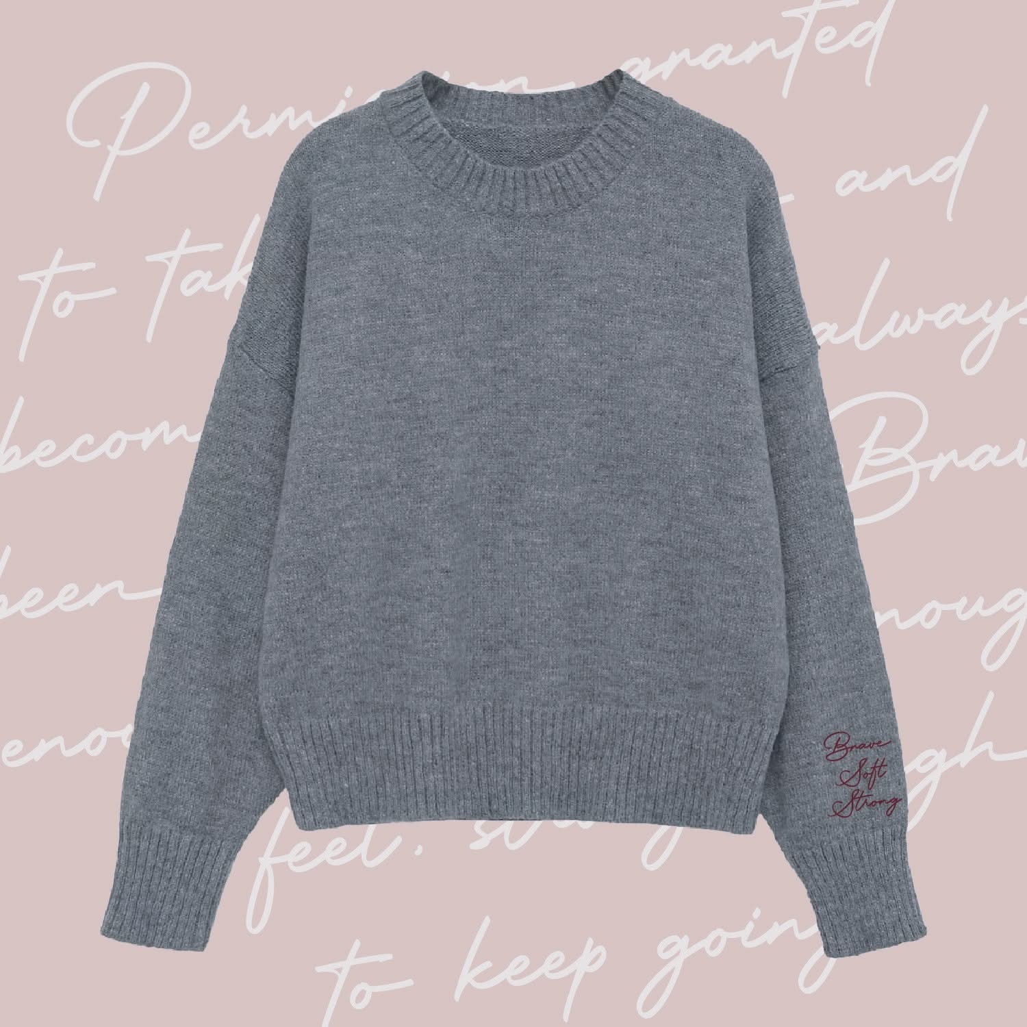 Gray sweater with "Brave, Soft, Strong" embroidered on the sleeve, seen on flat lay - Little Mama Shirt Shop