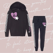 Child black sweater and joggers with checkers pattern on arm and leg, and Purple Heart with 'be you' in it flanked by a white star, seen on flat lay - Little Mama Shirt Shop