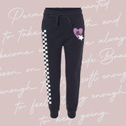 Child black joggers with checkers pattern on leg, and Purple Heart with 'be you' in it flanked by a white star, seen on flat lay - Little Mama Shirt Shop