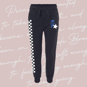 Child black joggers with checkers pattern on leg, and blue lightning bolt with 'be you' in it flanked by a white star, seen on flat lay - Little Mama Shirt Shop