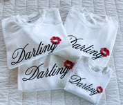 Adult white sweaters with "Darling" script and lipstick kiss design, shown on flat lay  – Little Mama Shirt Shop
