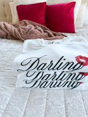 Stack of adult white sweater with "Darling" script and lipstick kiss design, shown on model  – Little Mama Shirt Shop