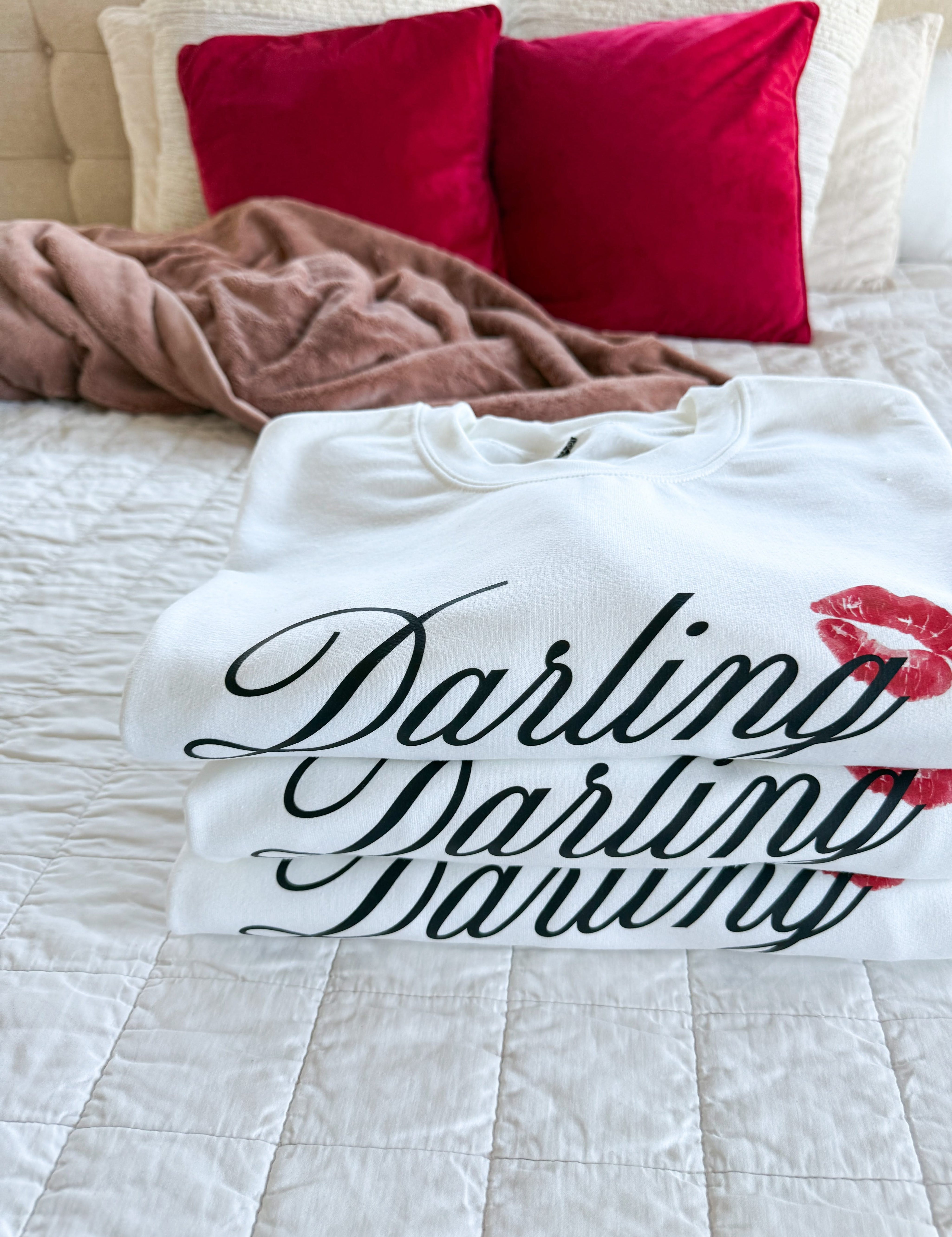 Stack of adult white sweater with "Darling" script and lipstick kiss design, shown on model  – Little Mama Shirt Shop