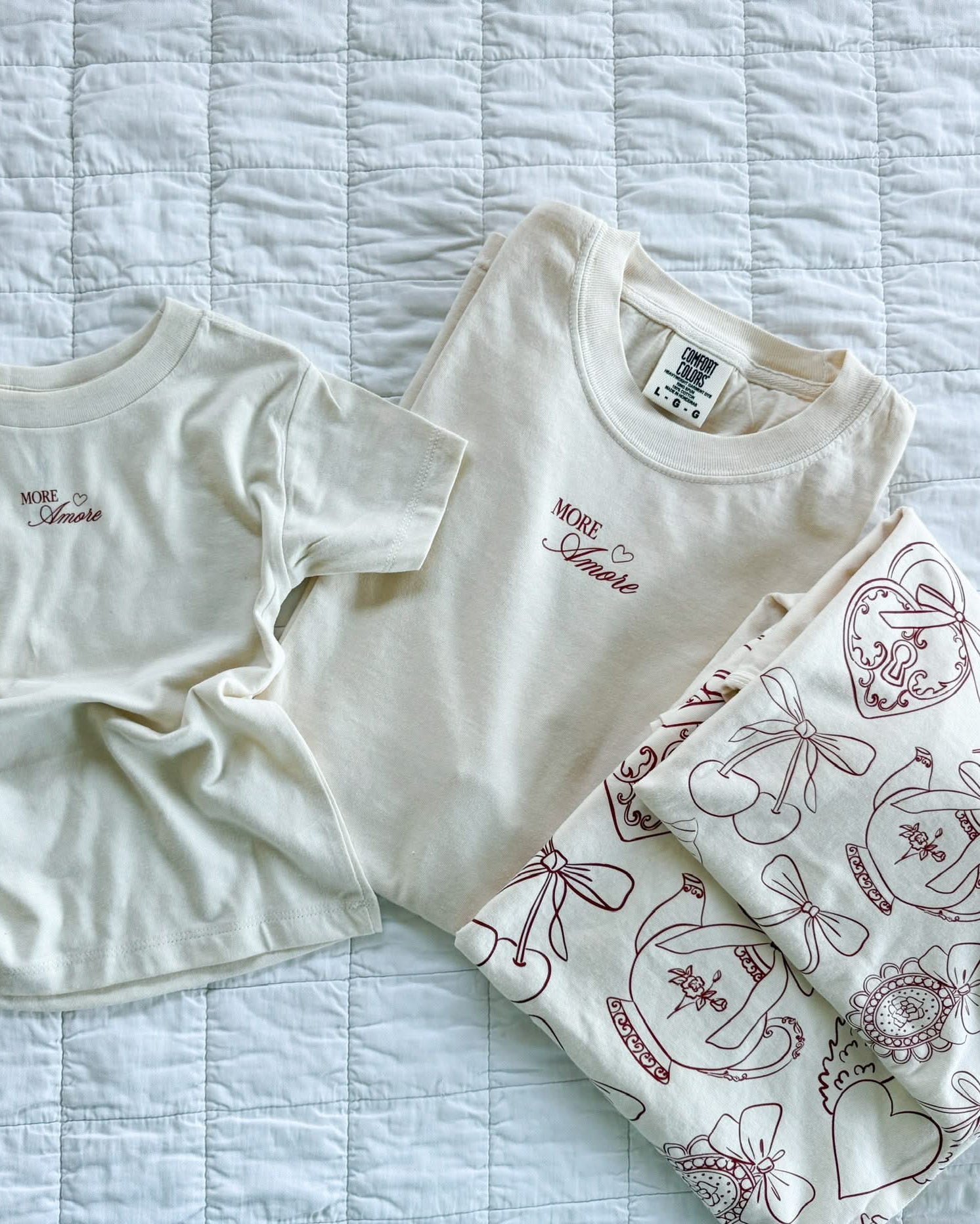 Adult and Child tee in ivory with "More Amore" print on front and Valentines collage design on back, shown on flat lay – Little Mama Shirt Shop