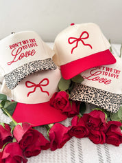 Adult cream and leopard hat with "Don't We Try To Love Love" design embroidered on front, shown on flat lay – Little Mama Shirt Shop