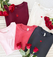 Adult tees in maroon, natural, soft pink, vintage red, and dark gray with mini symbol designs on front, shown on flat lay – Little Mama Shirt Shop