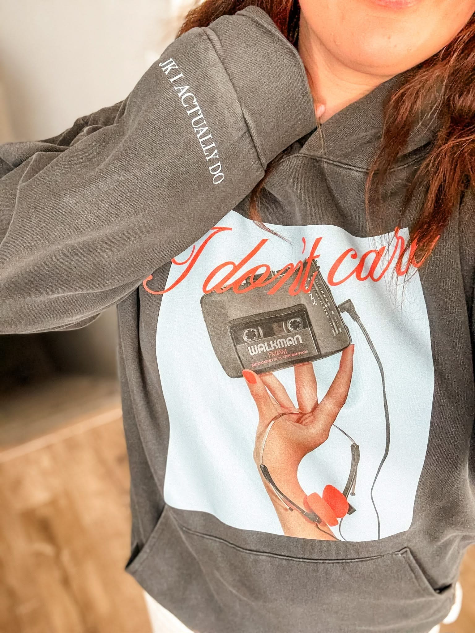 Adult black hoodie with "I Don't Care" retro cassette on front and "JK I Actually Do" text on sleeve, shown on model  – Little Mama Shirt Shop
