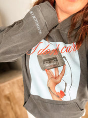 Adult black hoodie with "I Don't Care" retro cassette on front and "JK I Actually Do" text on sleeve, shown on model  – Little Mama Shirt Shop