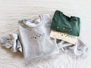 Ash adult basic fleece and green and ivory CC tees with lucky charm marshmallows embroidered on chest, seen on flat lay - Little Mama Shirt Shop