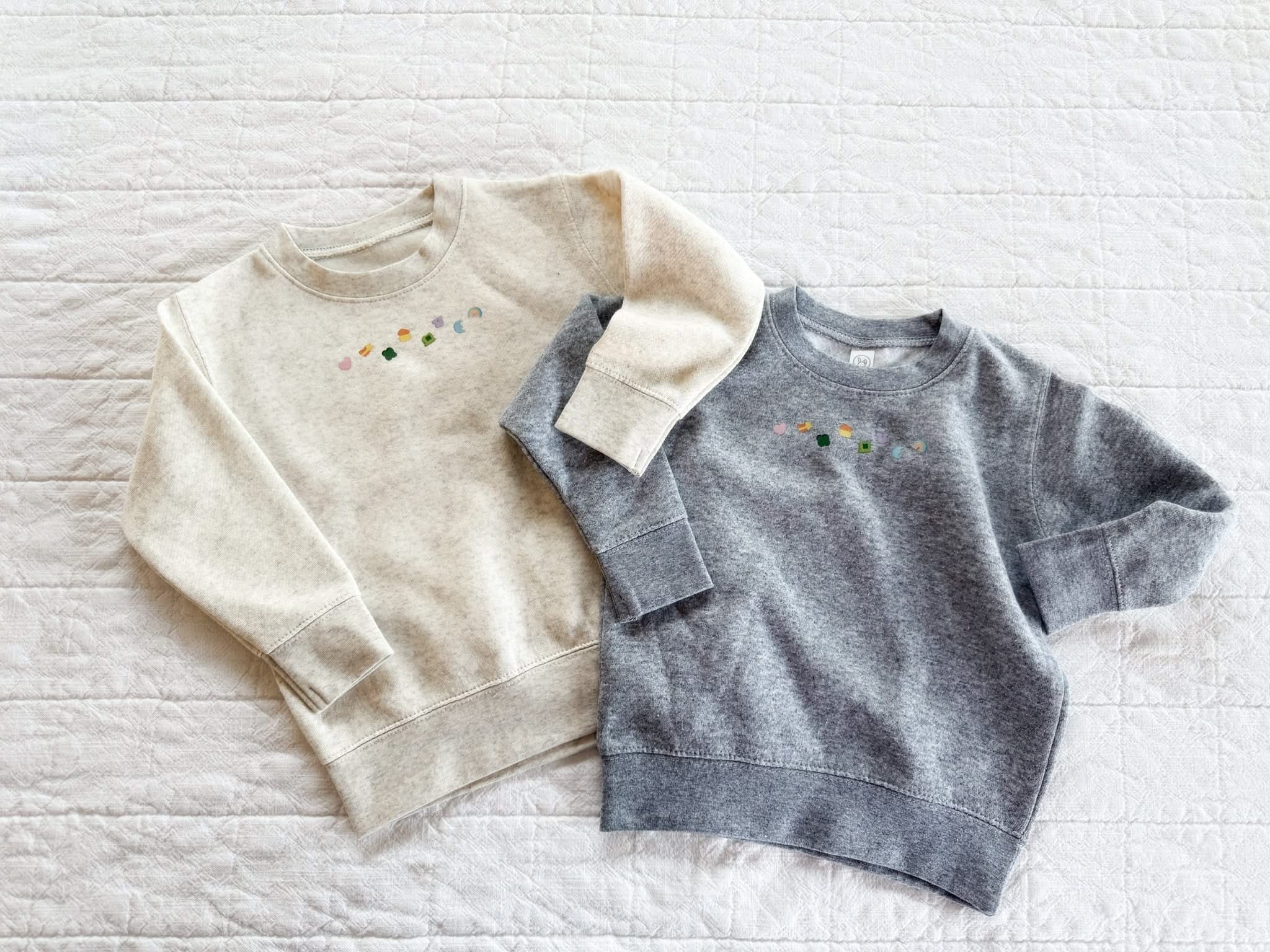Natural heather and gray child sweater with printed lucky charm marshmallows design on chest, seen on flat lay - Little Mama Shirt Shop
