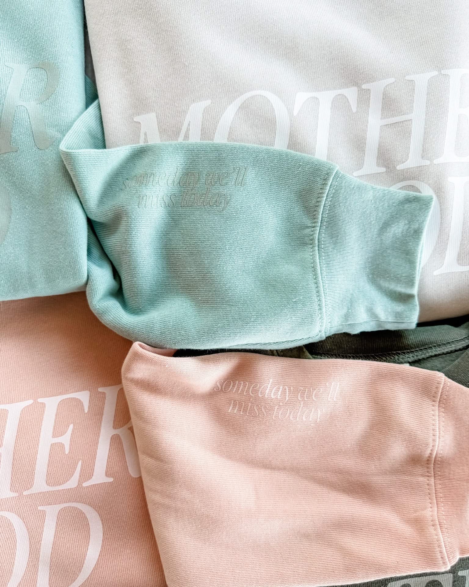 Adult fleece in army green, cream, blush, and mint with 'motherhood' printed on the front in tone on tone and 'someday we'll miss today' printed on sleeve, seen on flat lay - Little Mama Shirt Shop