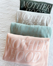 Adult fleece in army green, cream, blush, and mint with 'motherhood' printed on the front in tone on tone, seen on flat lay - Little Mama Shirt Shop