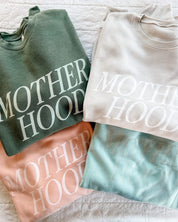 Adult fleece in army green, cream, blush, and mint with 'motherhood' printed on the front in tone on tone, seen on flat lay - Little Mama Shirt Shop