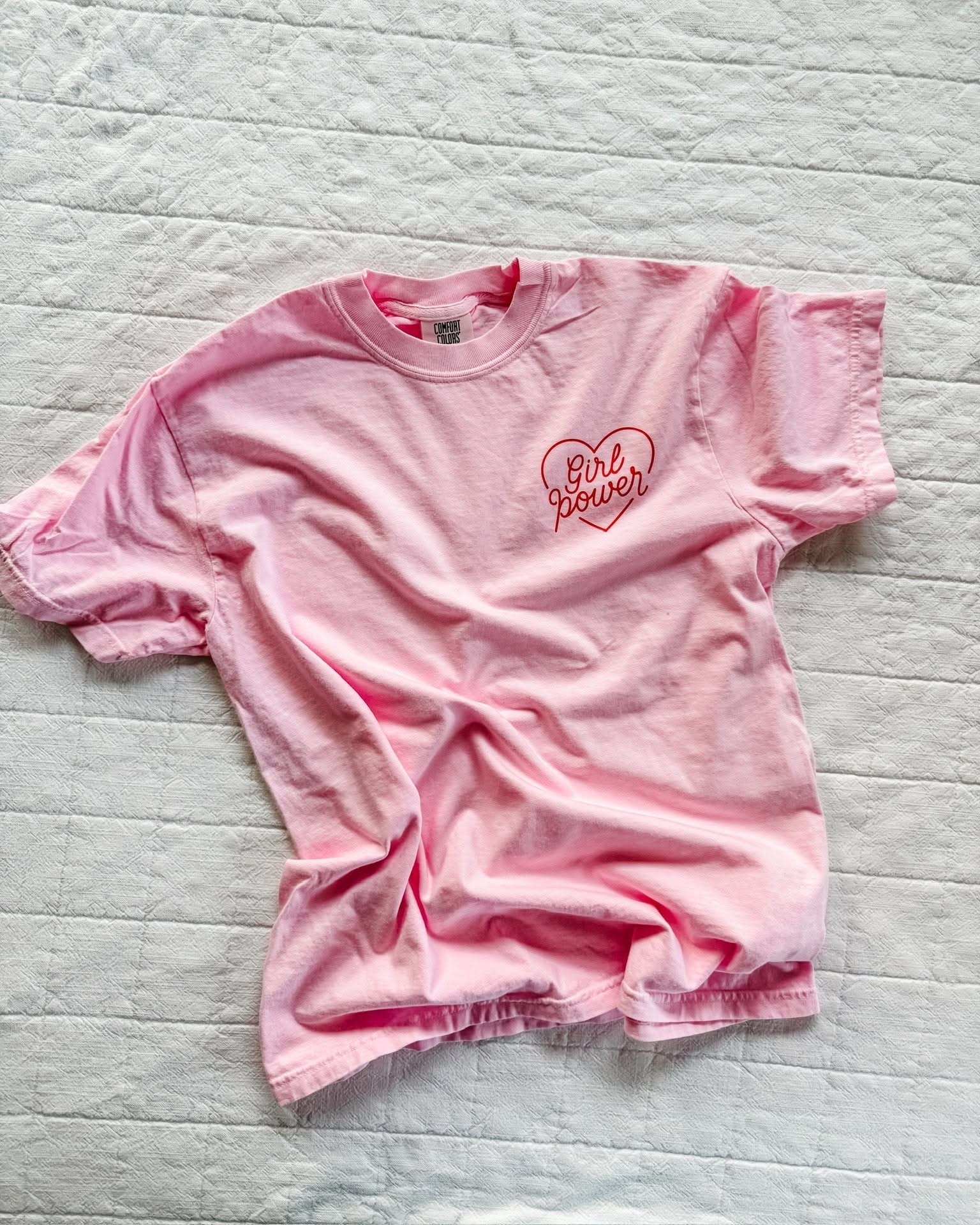 Youth blossom comfort colors tee with girl power script in heart design on pocket, seen on flat lay - Little Mama Shirt Shop