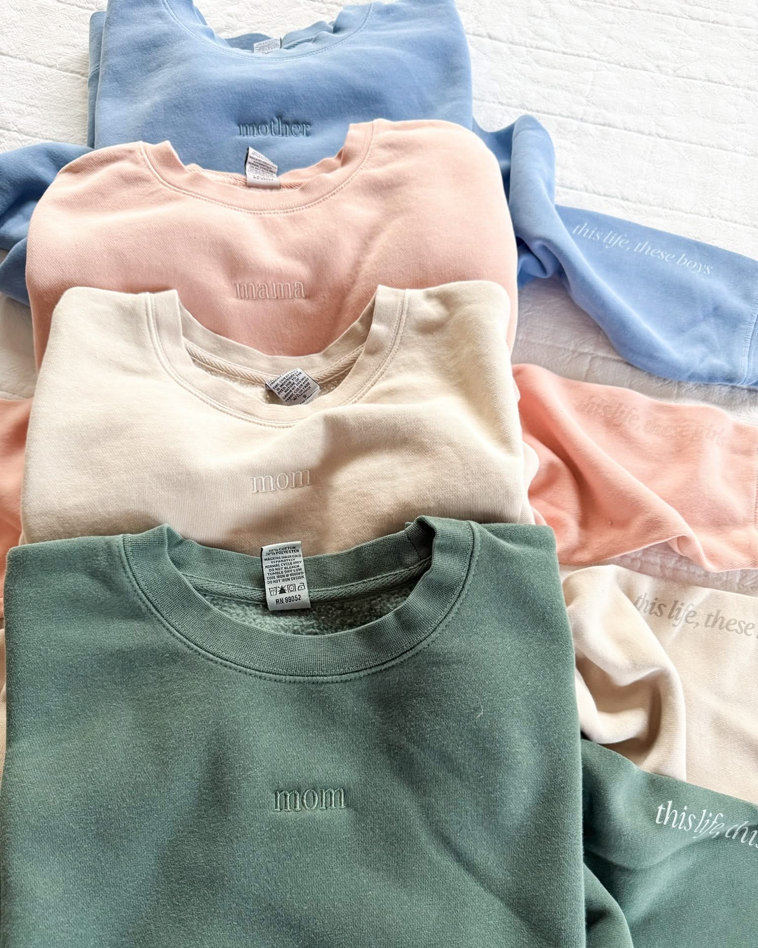 Adult crewneck in alpine, cream, blush, and light blue with mama, mom, or mother embroidered on the chest, seen on flat lay - Little Mama Shirt Shop