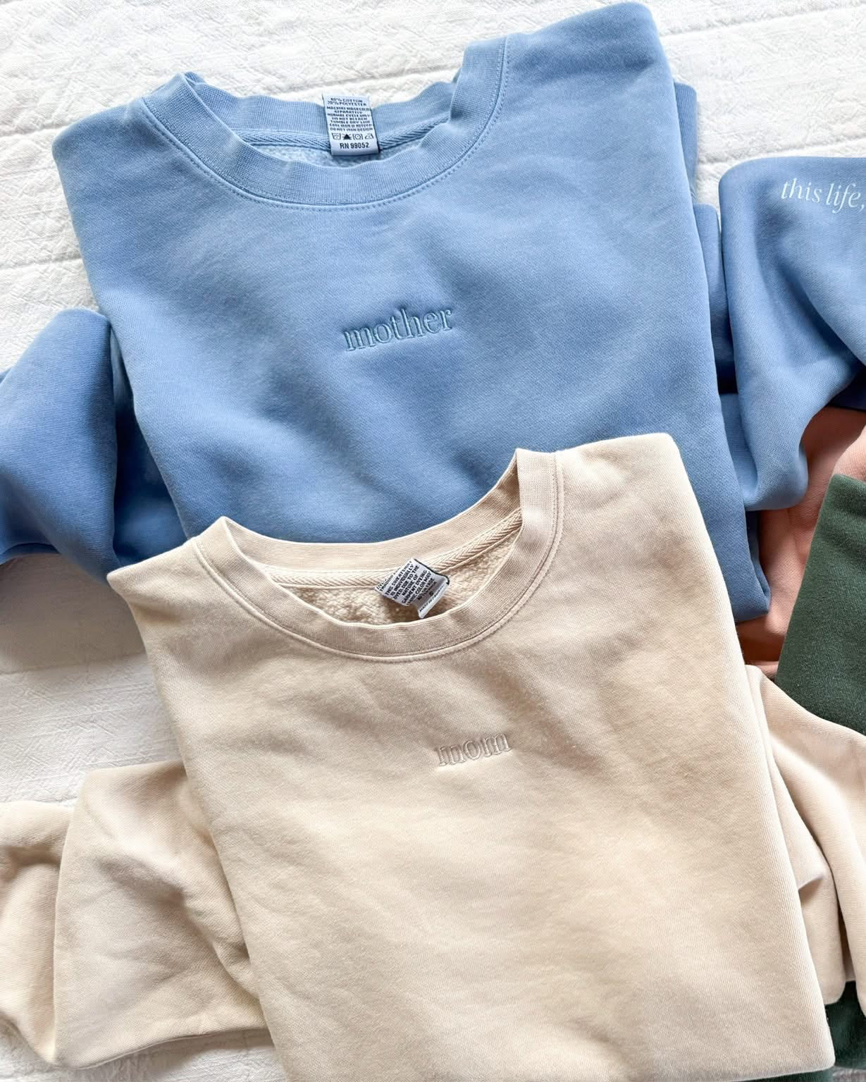 Adult crewneck in cream and light blue with mother and mom embroidered on the chest, seen on flat lay - Little Mama Shirt Shop