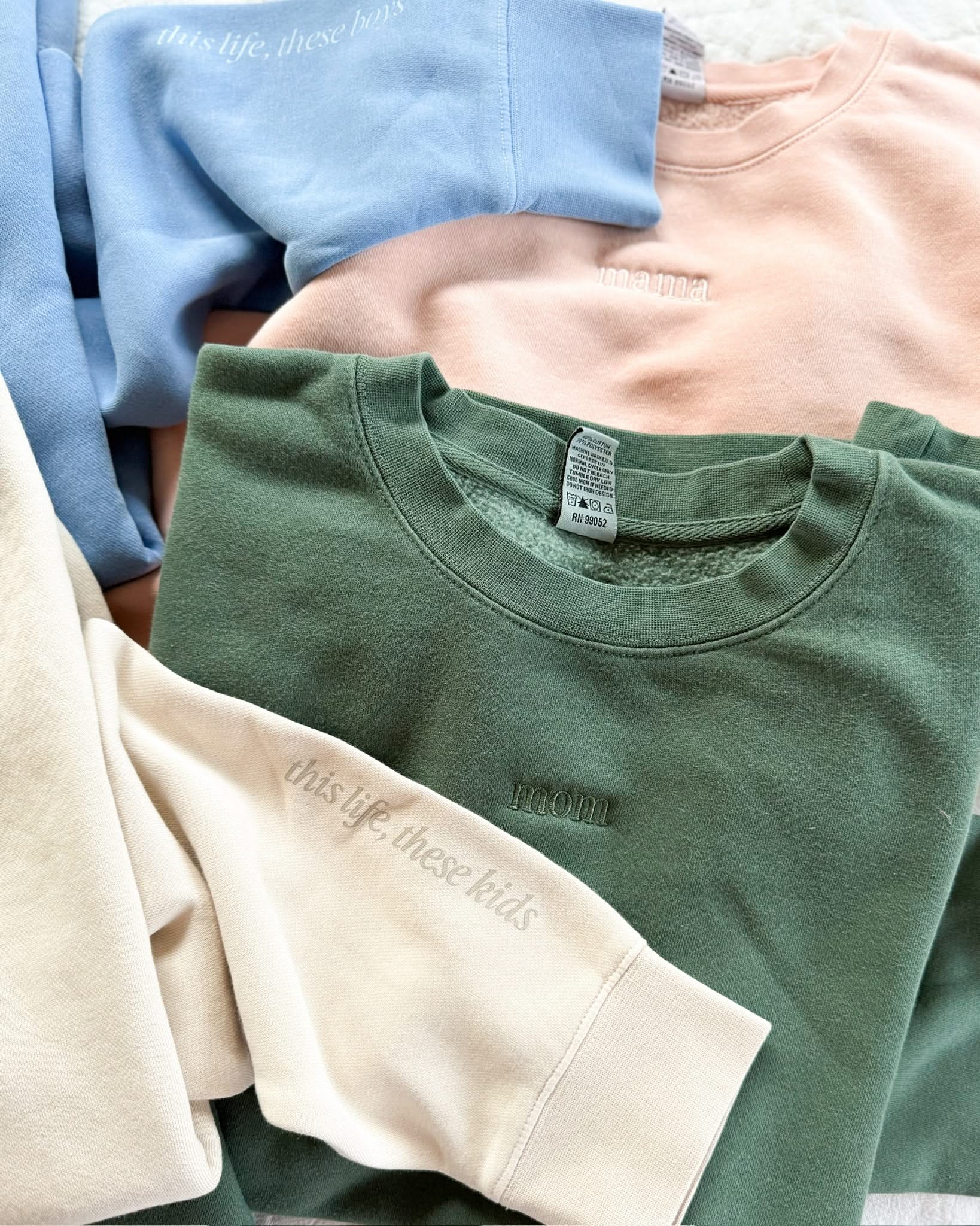 Adult crewneck in alpine and blush with mama and mom embroidered on the chest, seen on flat lay - Little Mama Shirt Shop