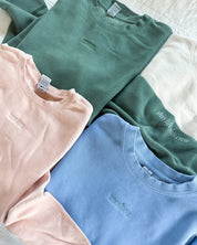 Adult crewneck in alpine, cream, blush, and light blue with mama, mom, or mother embroidered on the chest, seen on flat lay - Little Mama Shirt Shop