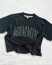 Adult boxy tee in black with 'mommin' printed on the front in puff print, seen on flat lay - Little Mama Shirt Shop