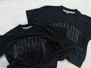 Adult boxy tee in black with 'mommin' printed on the front in puff print, seen on flat lay - Little Mama Shirt Shop