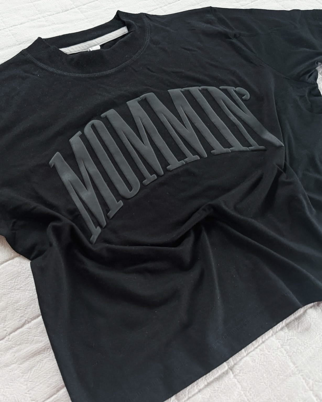 Adult boxy tee in black with 'mommin' printed on the front in puff print, seen on flat lay - Little Mama Shirt Shop