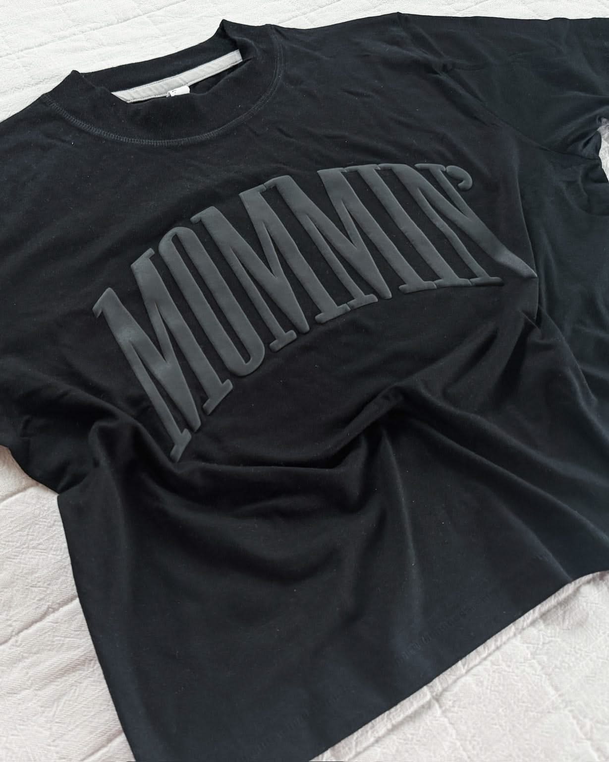 Adult boxy tee in black with 'mommin' printed on the front in puff print, seen on flat lay - Little Mama Shirt Shop