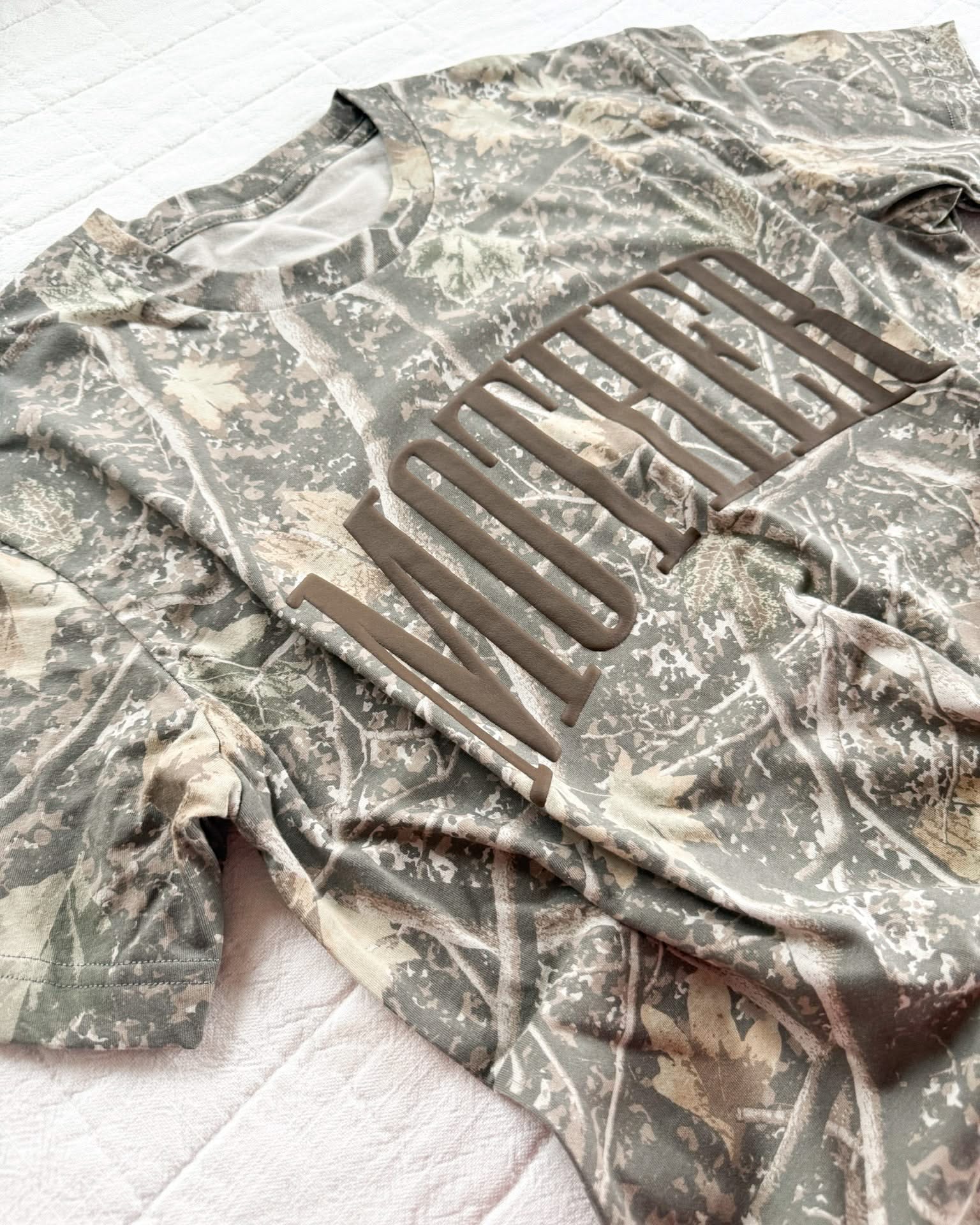 Adult camo tee with 'mother' printed on the front in puff print, seen on flat lay - Little Mama Shirt Shop