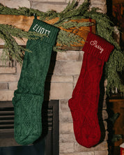 Christmas stocking in red and green with personalized name printed on cuff, shown on flat lay – Little Mama Shirt Shop