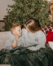 Child sweater in gray and adult sweater in sage with embroidered ski pattern, shown on model – Little Mama Shirt Shop