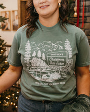 Comfort Colors Tee in light green with St. Nick's Christmas Tree Farm graphic on the front, shown on model – Little Mama Shirt Shop