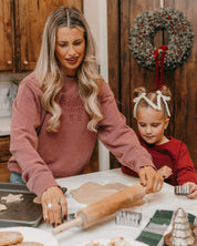 Adult sweater in dusty pink with 3 embroidered nutcrackers on chest, shown on model – Little Mama Shirt Shop