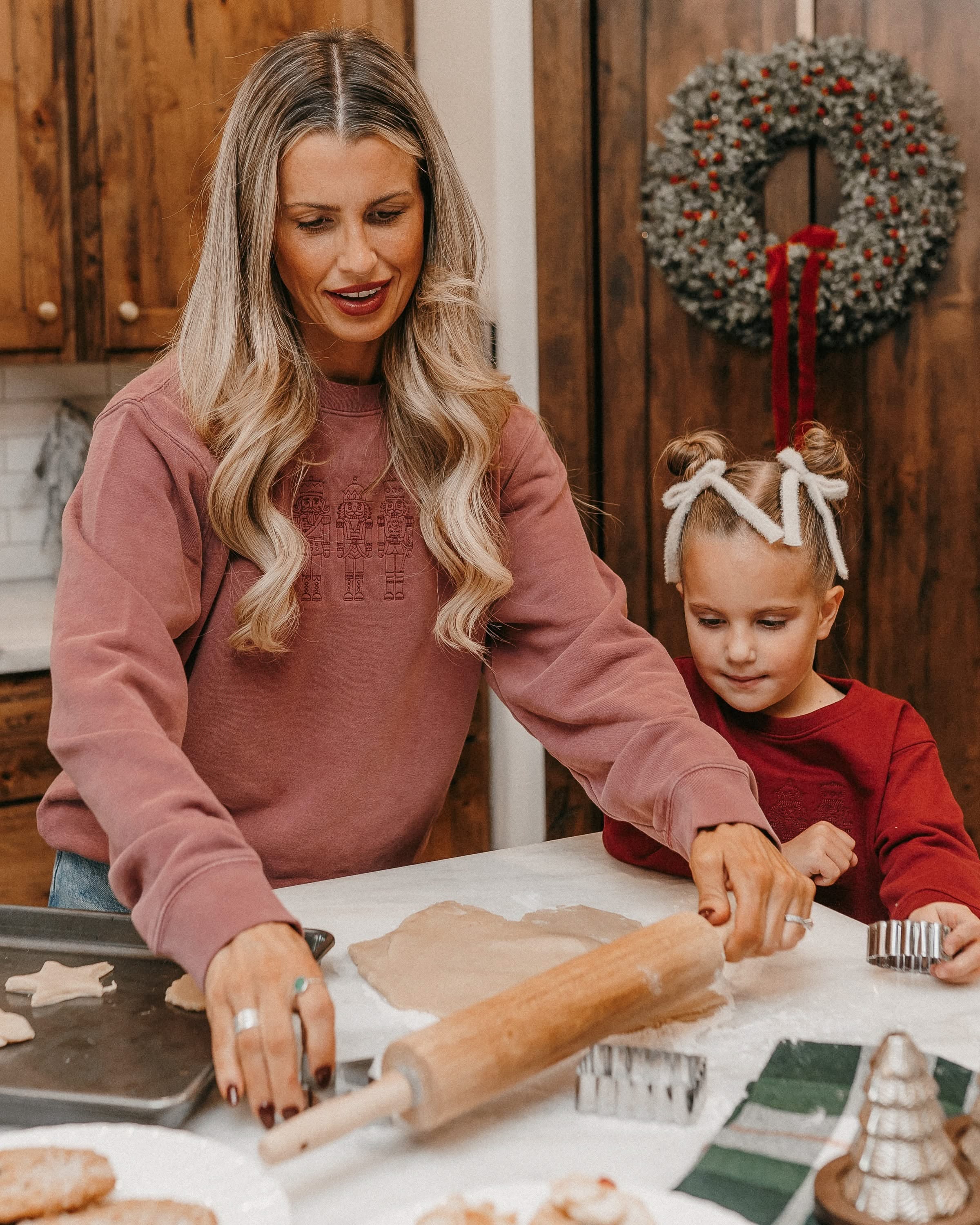 Adult sweater in dusty pink with 3 embroidered nutcrackers on chest, shown on model – Little Mama Shirt Shop