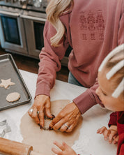 Adult sweater in dusty pink with 3 embroidered nutcrackers on chest, shown on model – Little Mama Shirt Shop