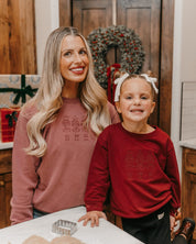 Adult sweater in dusty pink and child sweater in red with 3 embroidered nutcrackers on chest, shown on models – Little Mama Shirt Shop