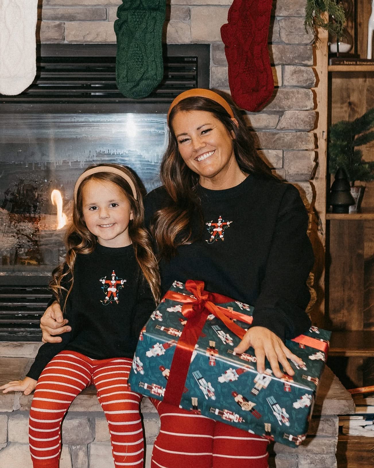 Adult and child sweaters in black with Santa wrapped in lights embroidery on front, shown on models – Little Mama Shirt Shop