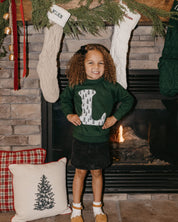 Child long sleeve in forest with Christmas patterned trees initial L on front, shown on model – Little Mama Shirt Shop