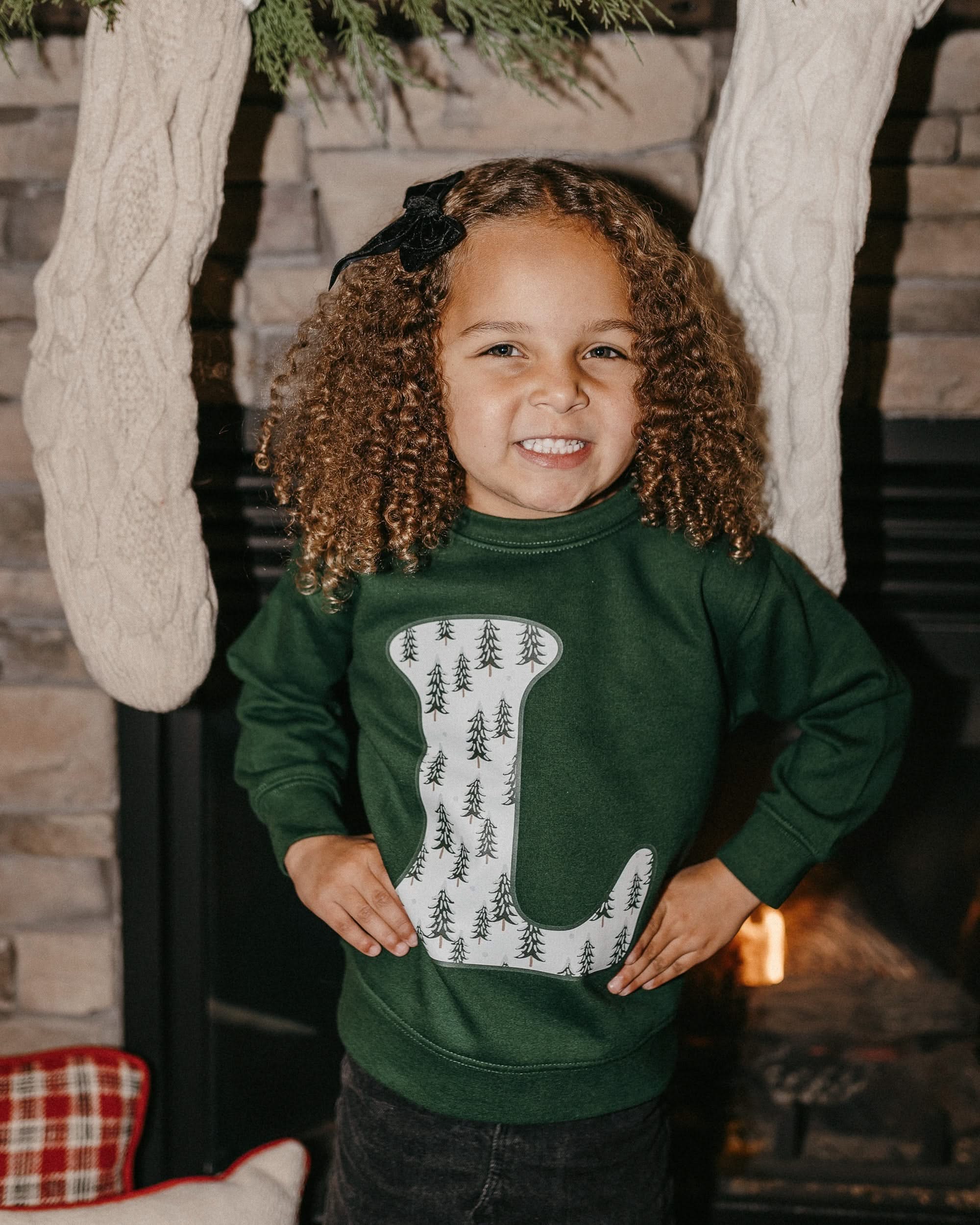 Child long sleeve in forest with Christmas patterned trees initial L on front, shown on model – Little Mama Shirt Shop