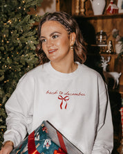 Adult sweater in white with 'back to December' and bow on chest, shown on model – Little Mama Shirt Shop