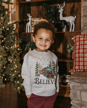 Child sweater in gray with winter train and 'Believe' on chest, shown on model – Little Mama Shirt Shop