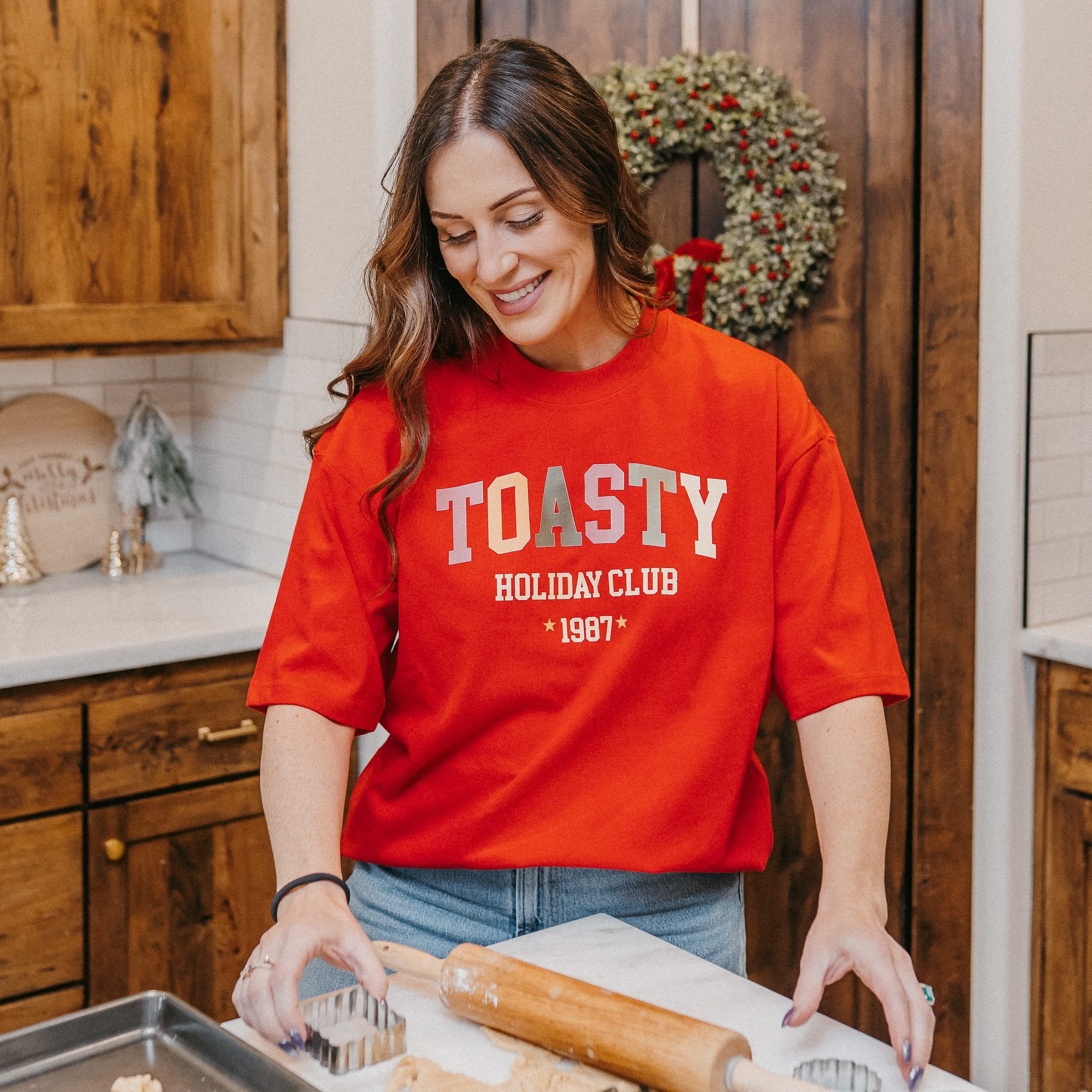 Adult heavy weight tee in red with 'toasty holiday club' design on front, shown on model – Little Mama Shirt Shop