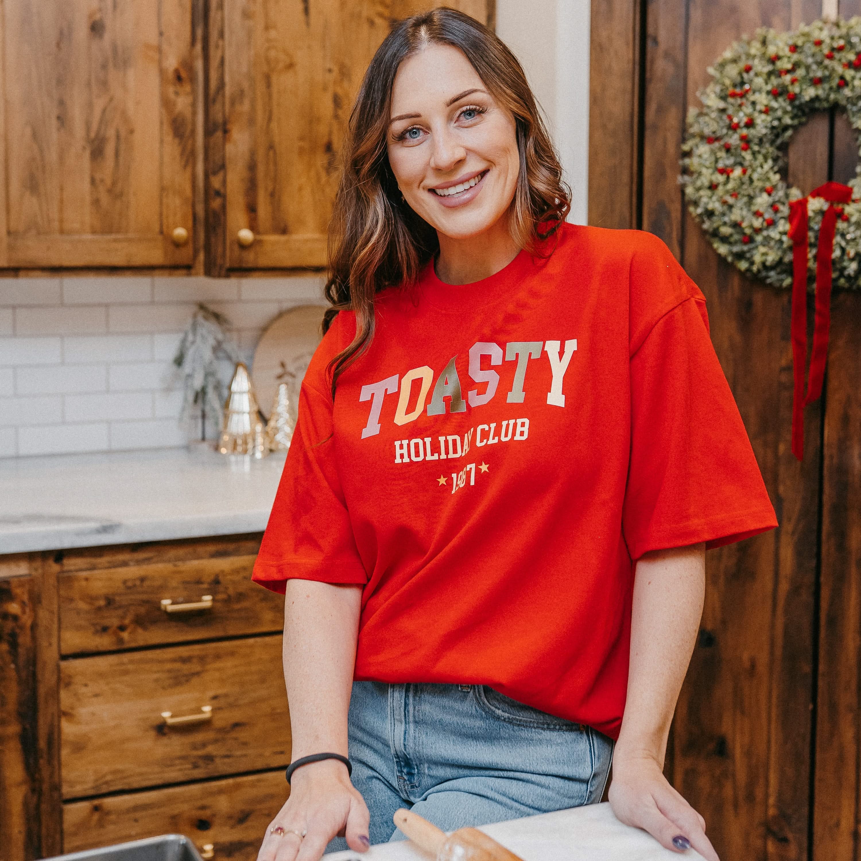 Adult heavy weight tee in red with 'toasty holiday club' design on front, shown on model – Little Mama Shirt Shop