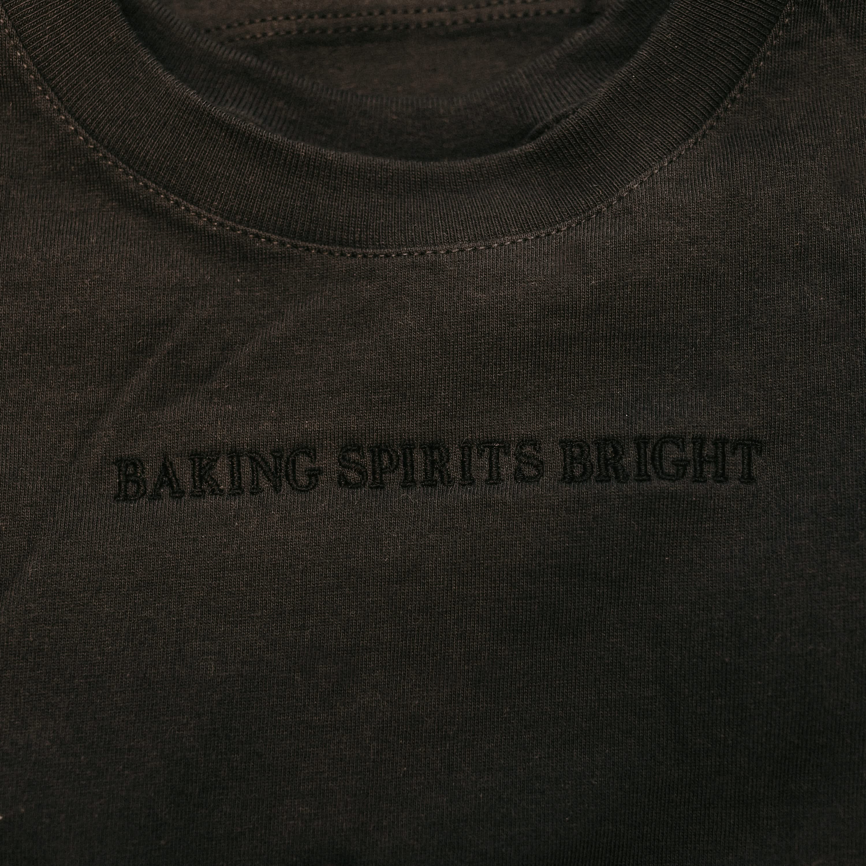 Adult tee in dark gray with Christmas message on front, shown on flat lay – Little Mama Shirt Shop