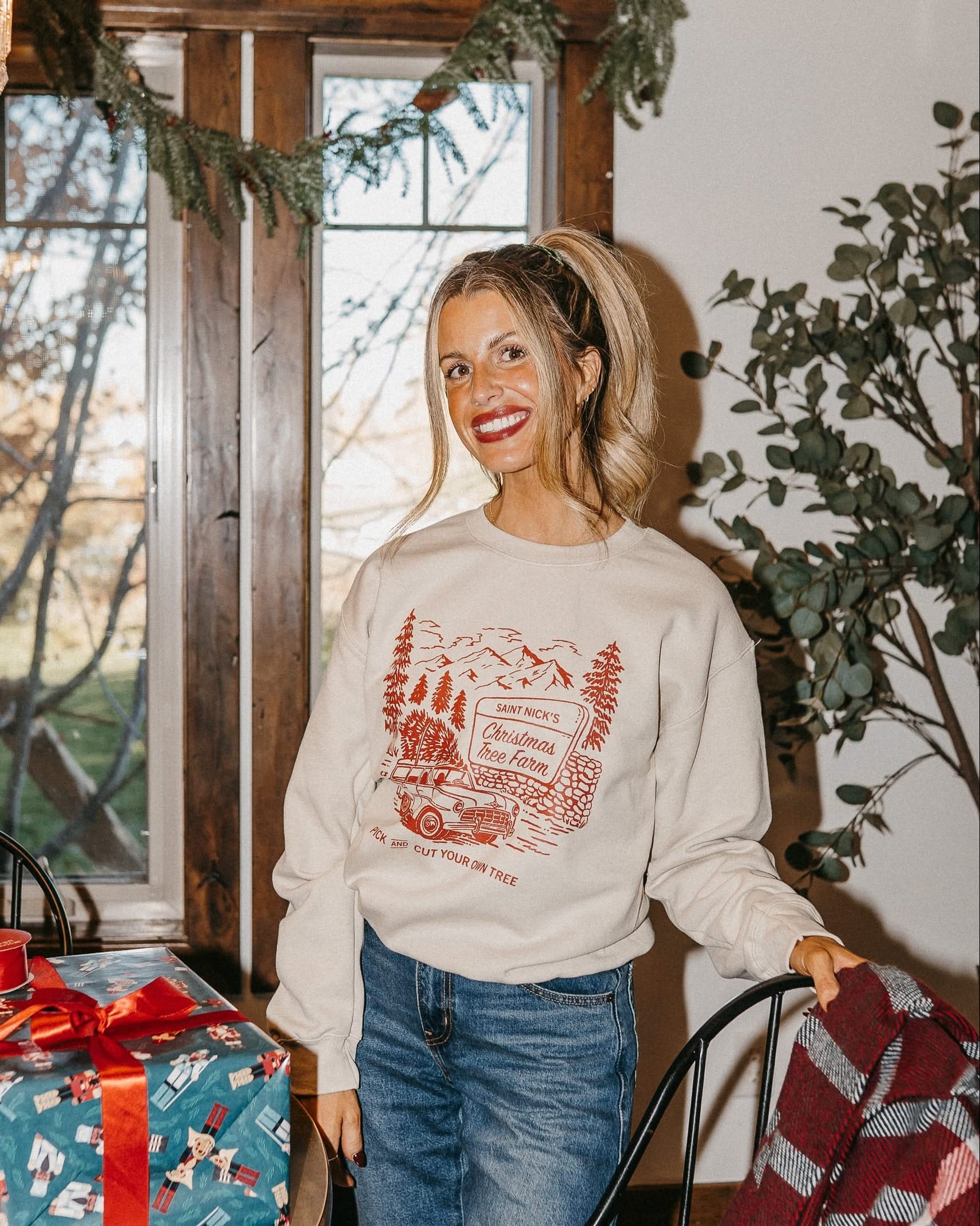 Adult basic fleece in sand with St. Nick's Christmas Tree Farm graphic on the front, shown on model – Little Mama Shirt Shop