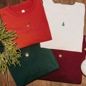 Adult tees in vintage red, vintage white, forest, and maroon with Christmas mini symbols on front, shown on flat lay – Little Mama Shirt Shop