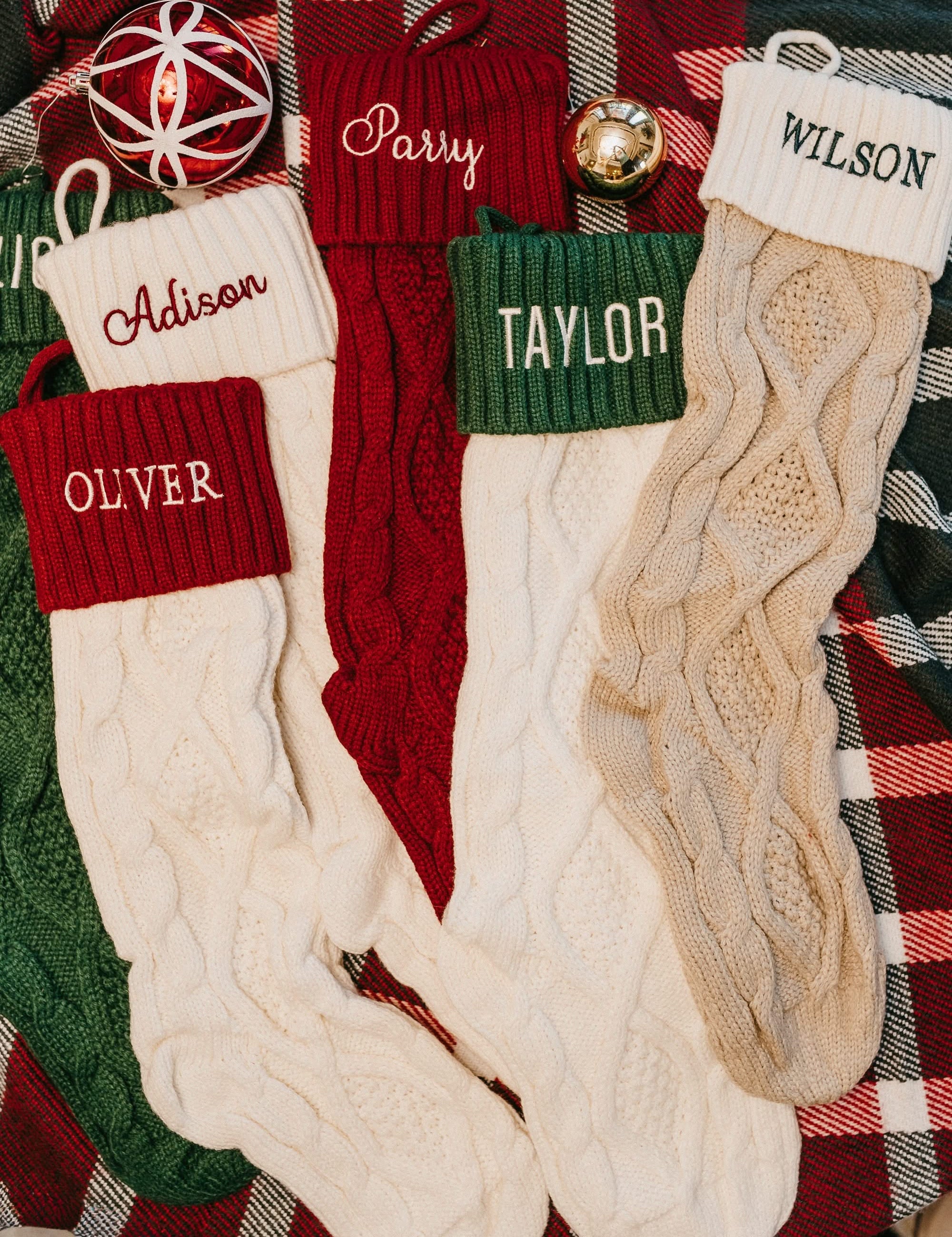 Christmas stocking in tan, cream, red, and green with personalized name printed on cuff, shown on flat lay – Little Mama Shirt Shop