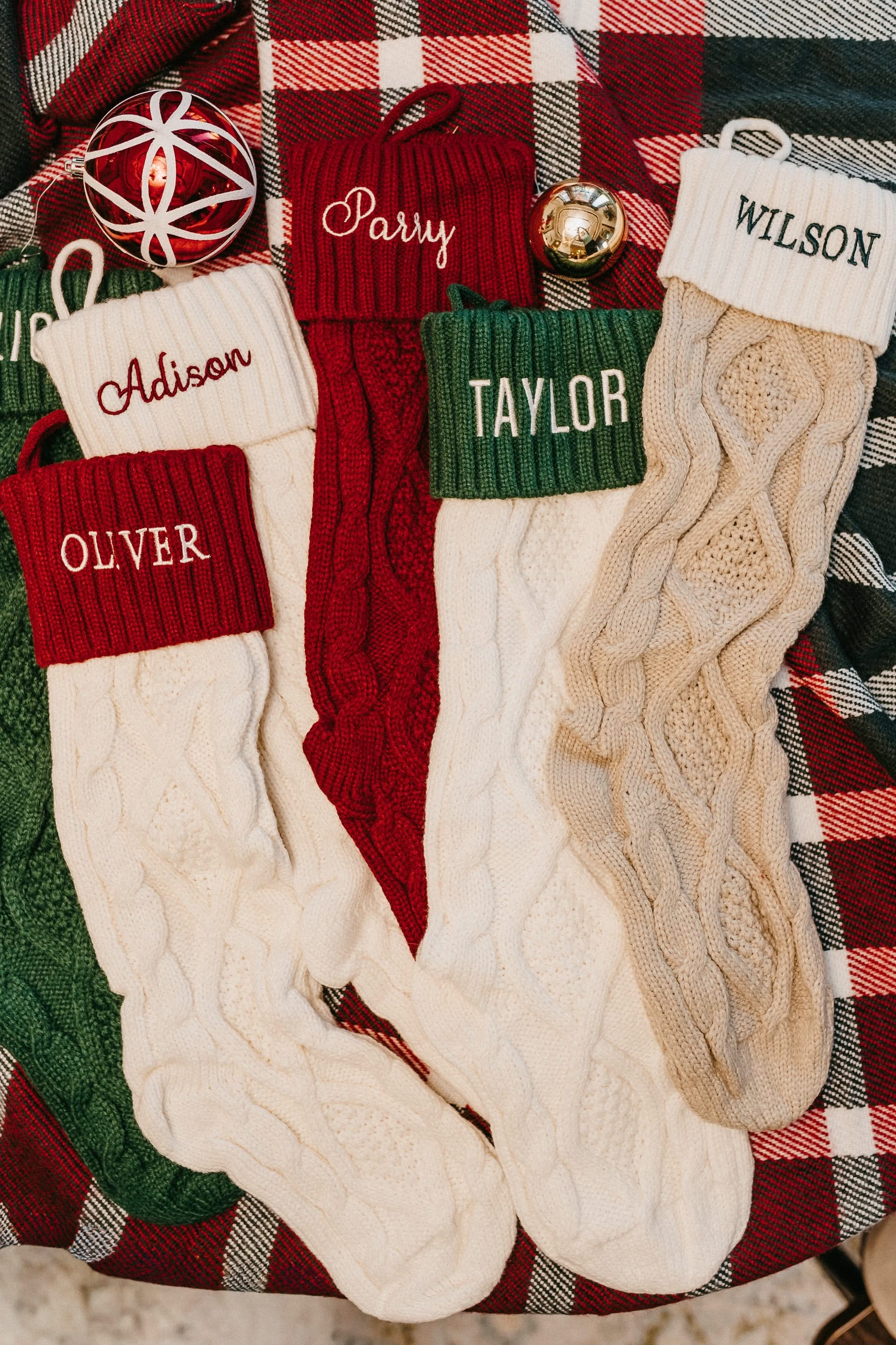Christmas stocking in tan, cream, red, and green with personalized name printed on cuff, shown on flat lay – Little Mama Shirt Shop